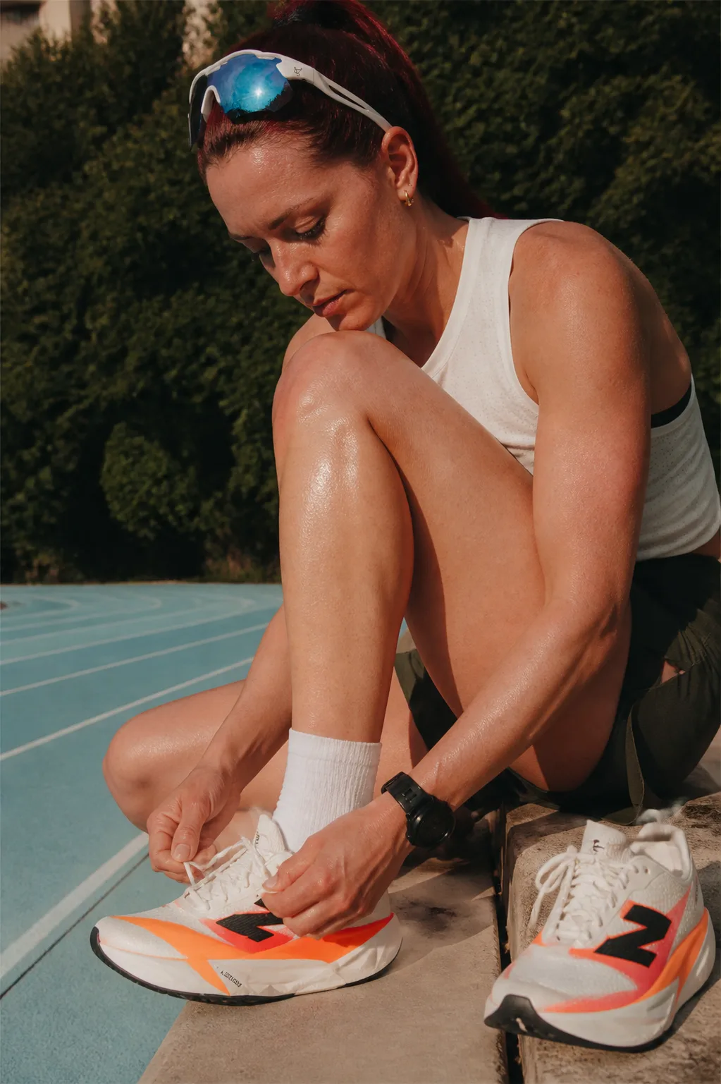 Runner seduta sulla pista mentre allaccia le scarpe